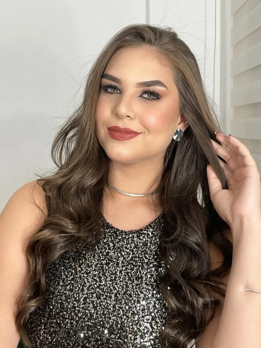 Cliente com make glam de festa, esfumado marcado e vestido de paetê