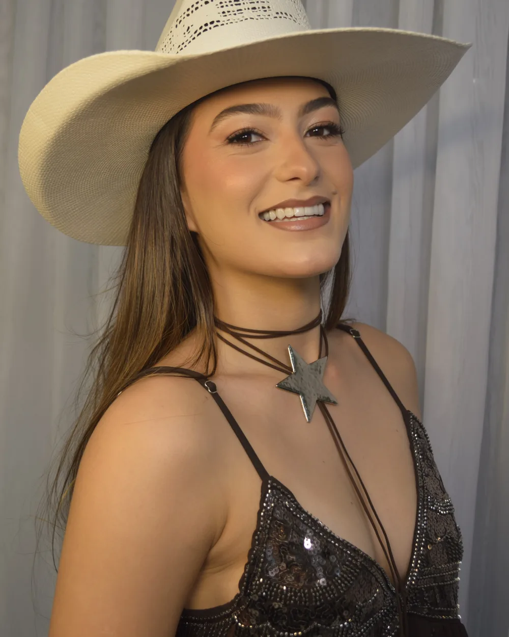 Cliente com make para Barretos: pele iluminada, chapéu e sorriso
