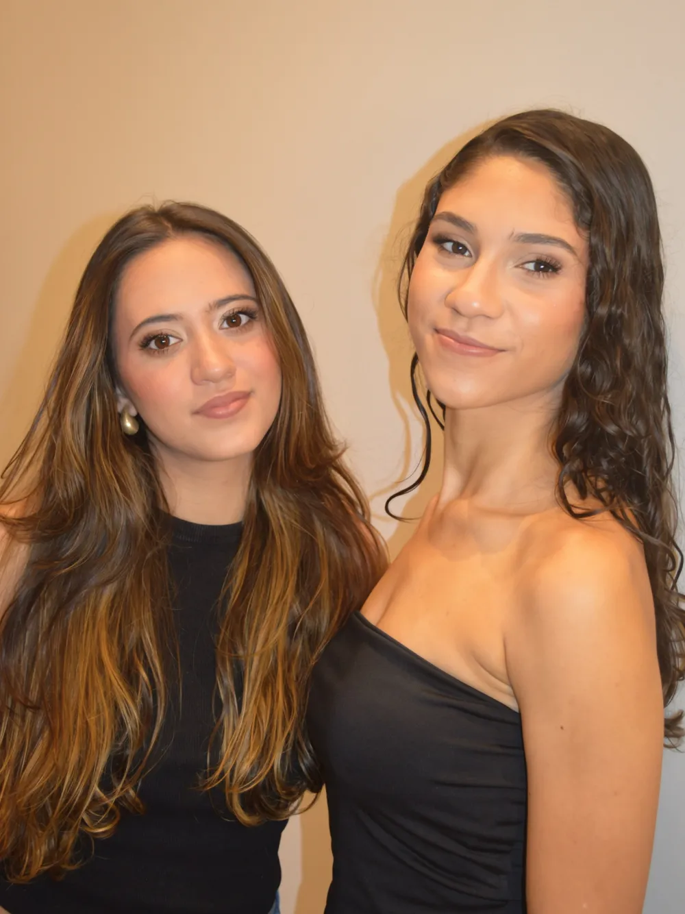Duas amigas maquiadas para festa, de preto, lado a lado